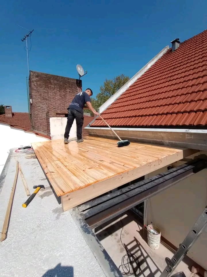 Trabajo sobre una estructura nueva de madera junto a un techo de tejas